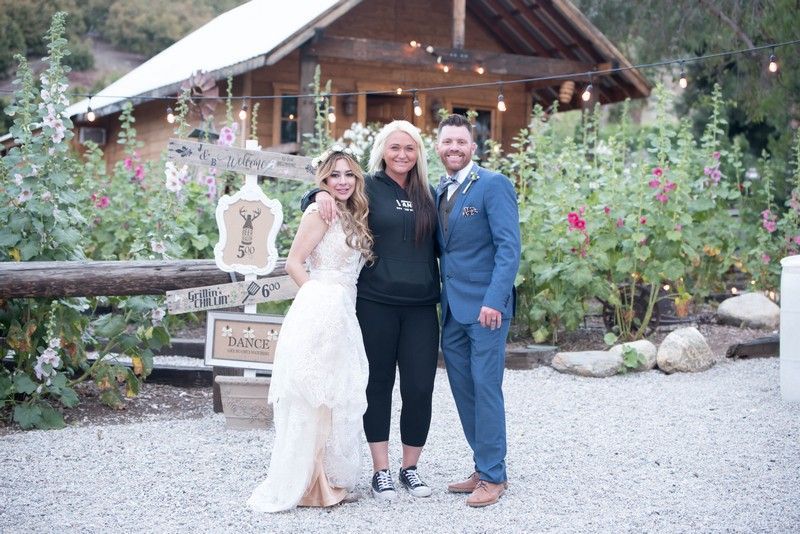 A bride and groom are posing for a picture in front of a cabin.