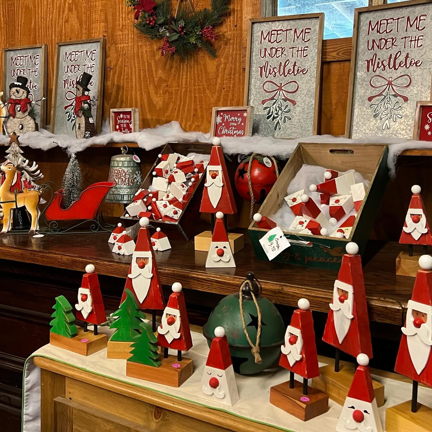 A shelf filled with Christmas decorations including santa clauses and trees.