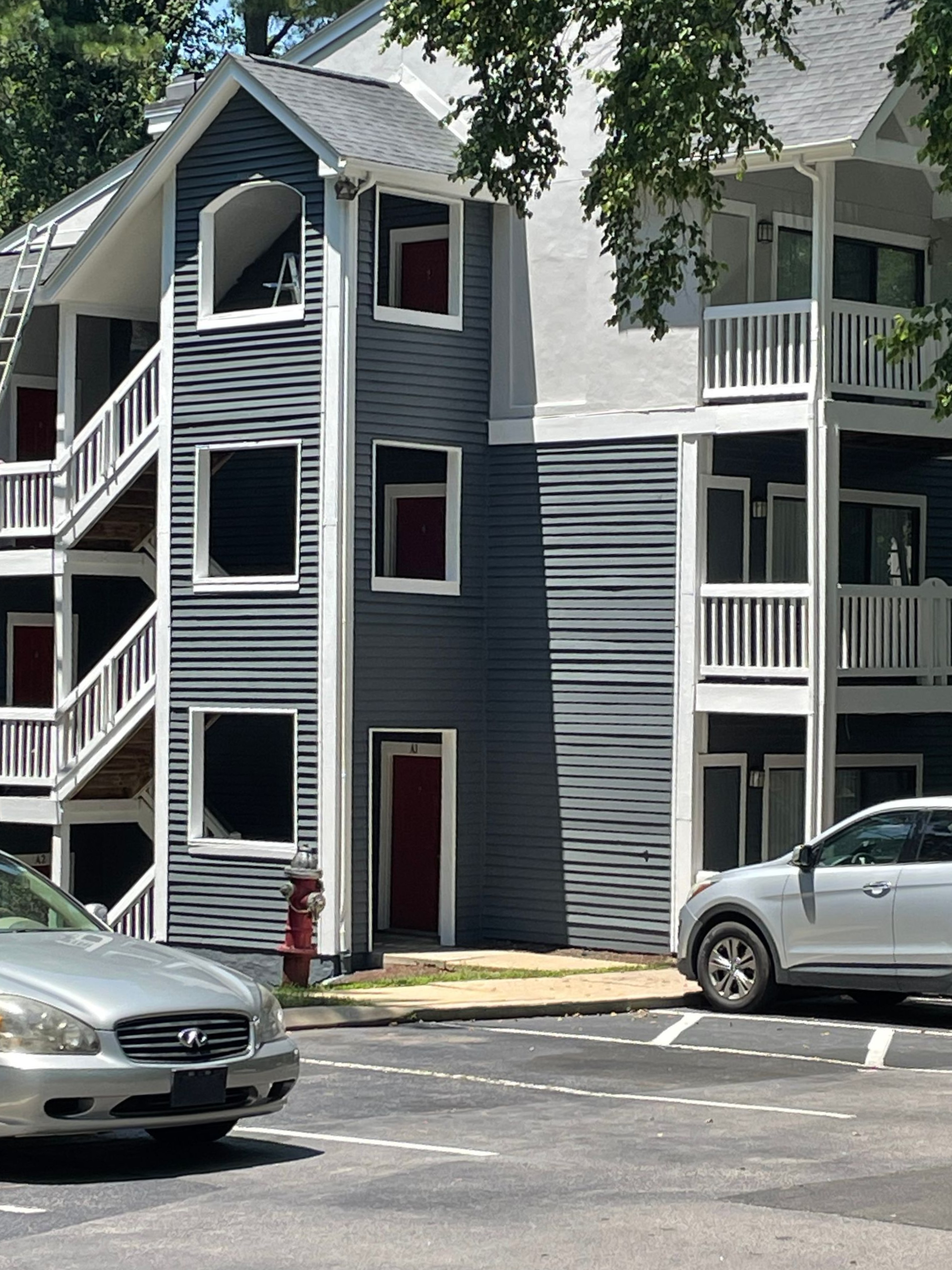 Multi-story apartment building with stairwells, parked cars, and fire hydrant.