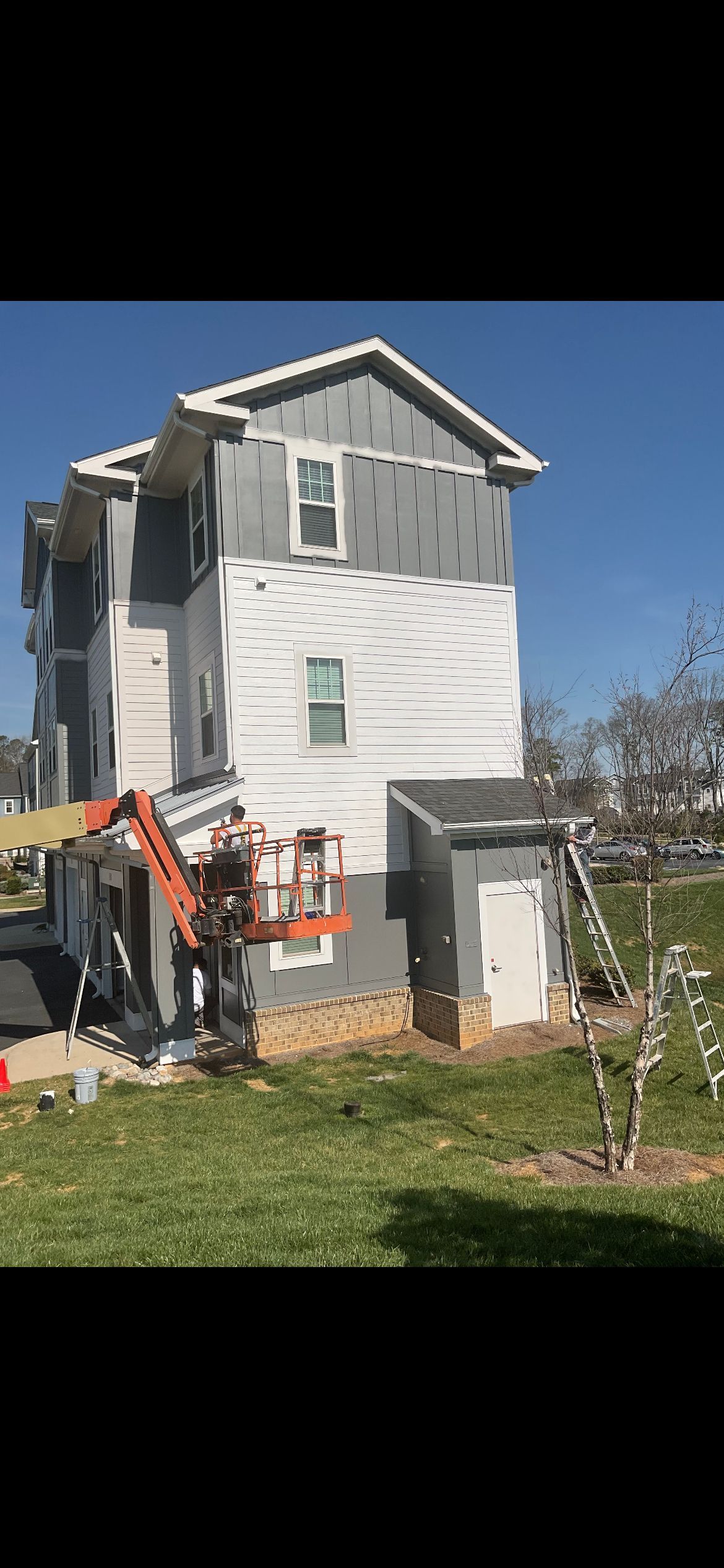 A building under construction with a lift on the side against a blue sky.