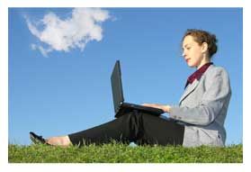 women typing on laptop A woman is sitting on the grass using a laptop computer.
