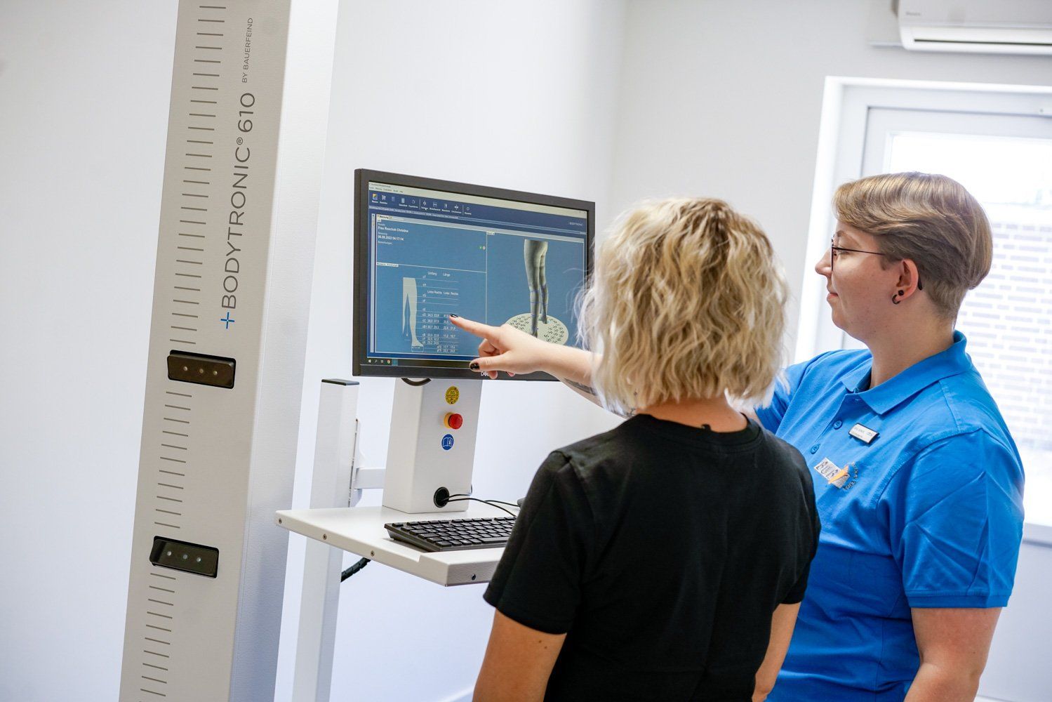 Eine Frau zeigt auf einen Computerbildschirm, während eine andere Frau zusieht.