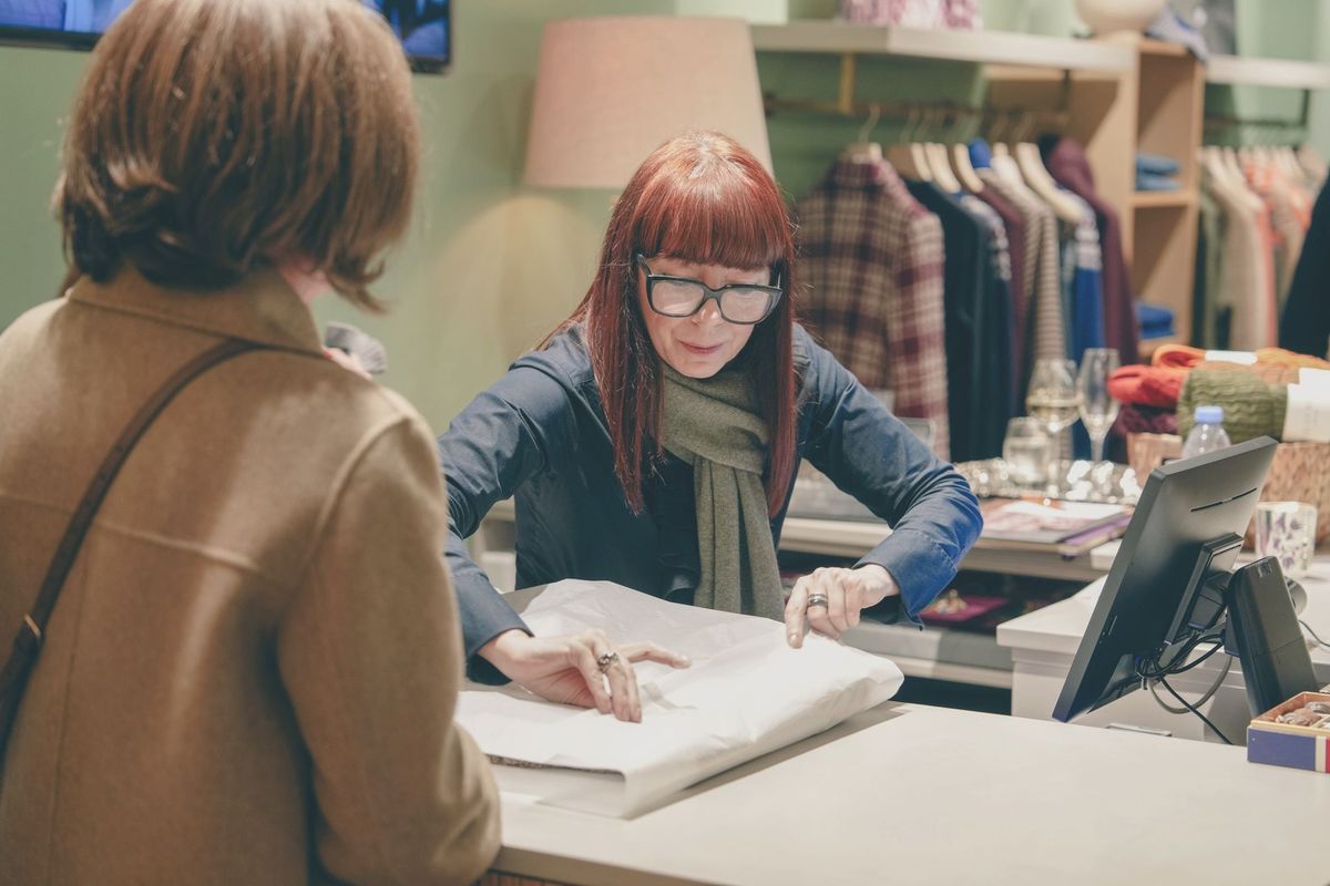 A shop assistant wrapping a purchase for a customer at a boutique counter, REGO Creative journal