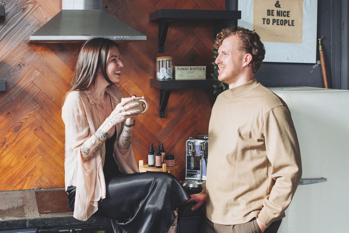 Two people laughing together in a café with wellness products on the shelves behind them, REGO Creative journal