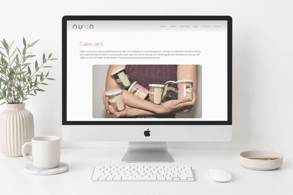 A desktop computer showing a brand website beside a plant and a cup of coffee, REGO Creative journal