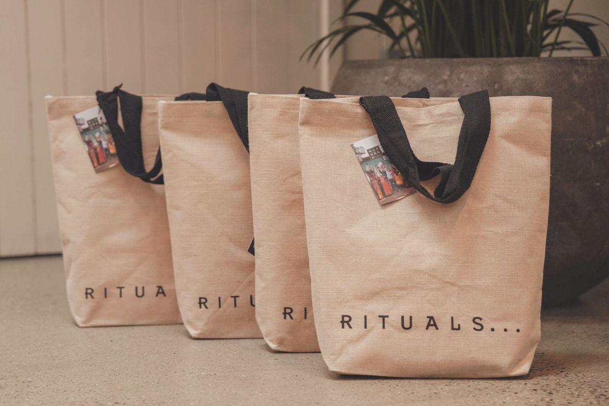 Canvas tote bags with black handles on display at a luxury brand event, REGO Creative journal