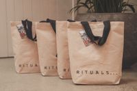 Canvas tote bags with black handles on display at a luxury brand event, REGO Creative journal