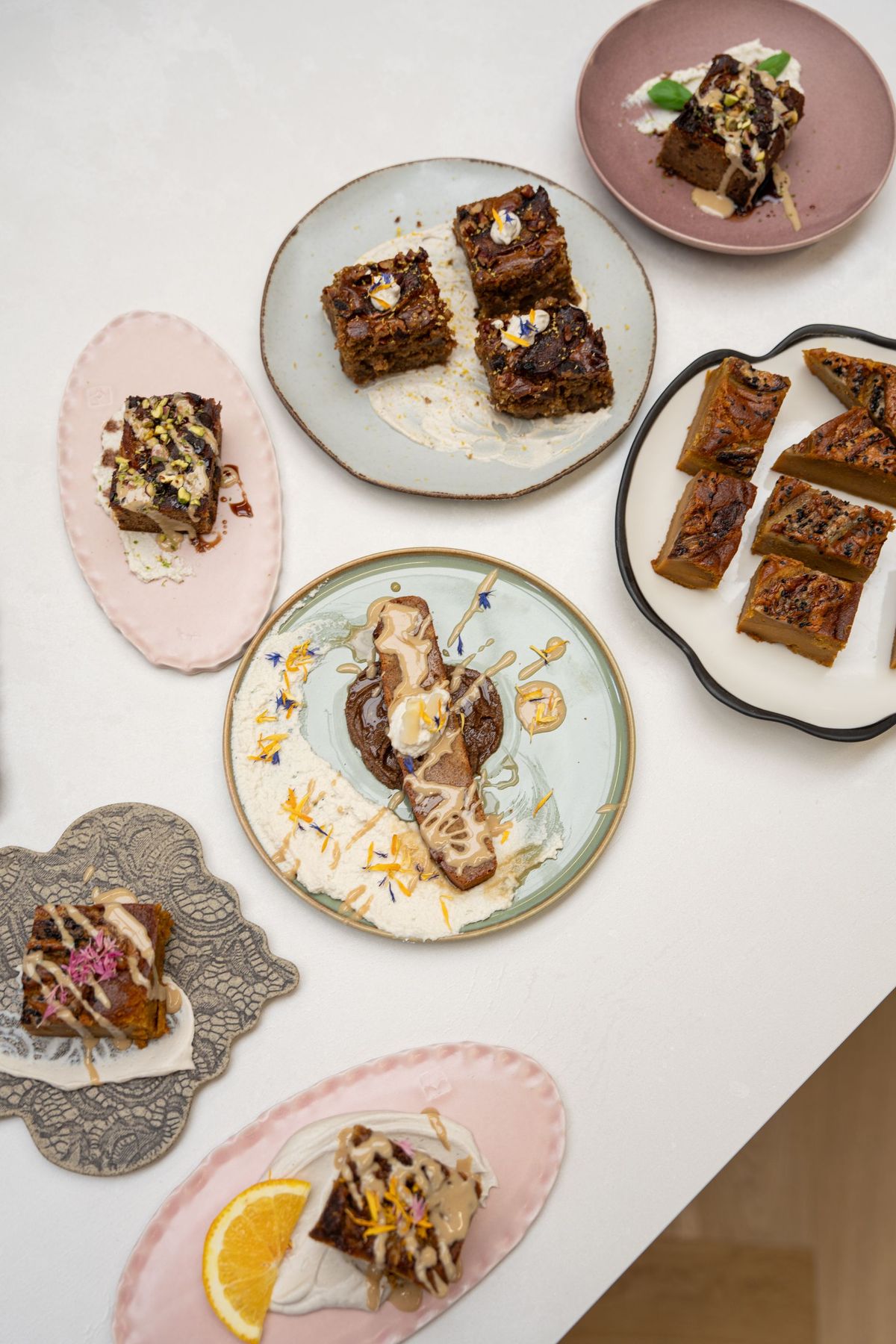 Plant-based cakes and sweet bakes with tahini and edible flowers on colourful ceramic plates, photographed from above, Bettina’s Kitchen by REGO Creative