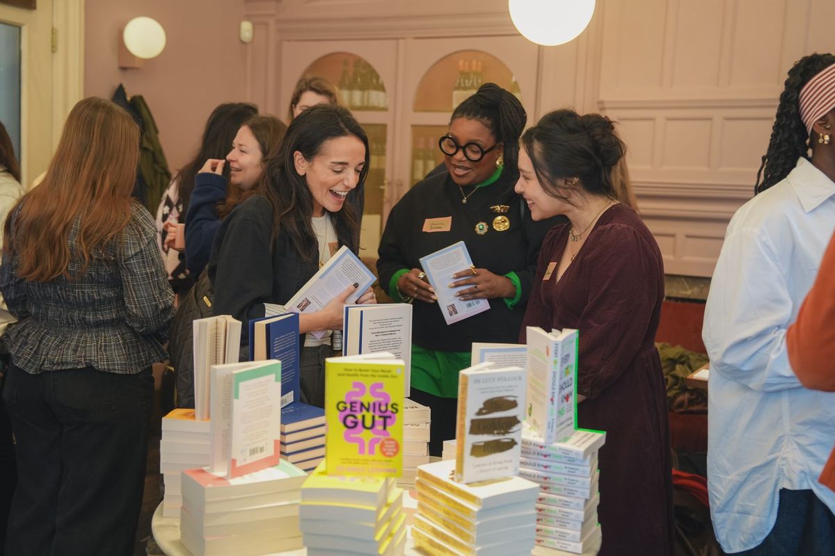 Guests laughing together over books at the Coral Press launch event, by REGO Creative