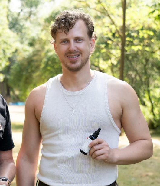 Aaron Davey, founder of Fungi Biotics, holding a Fungi Biotics tincture bottle outdoors, by REGO Creative