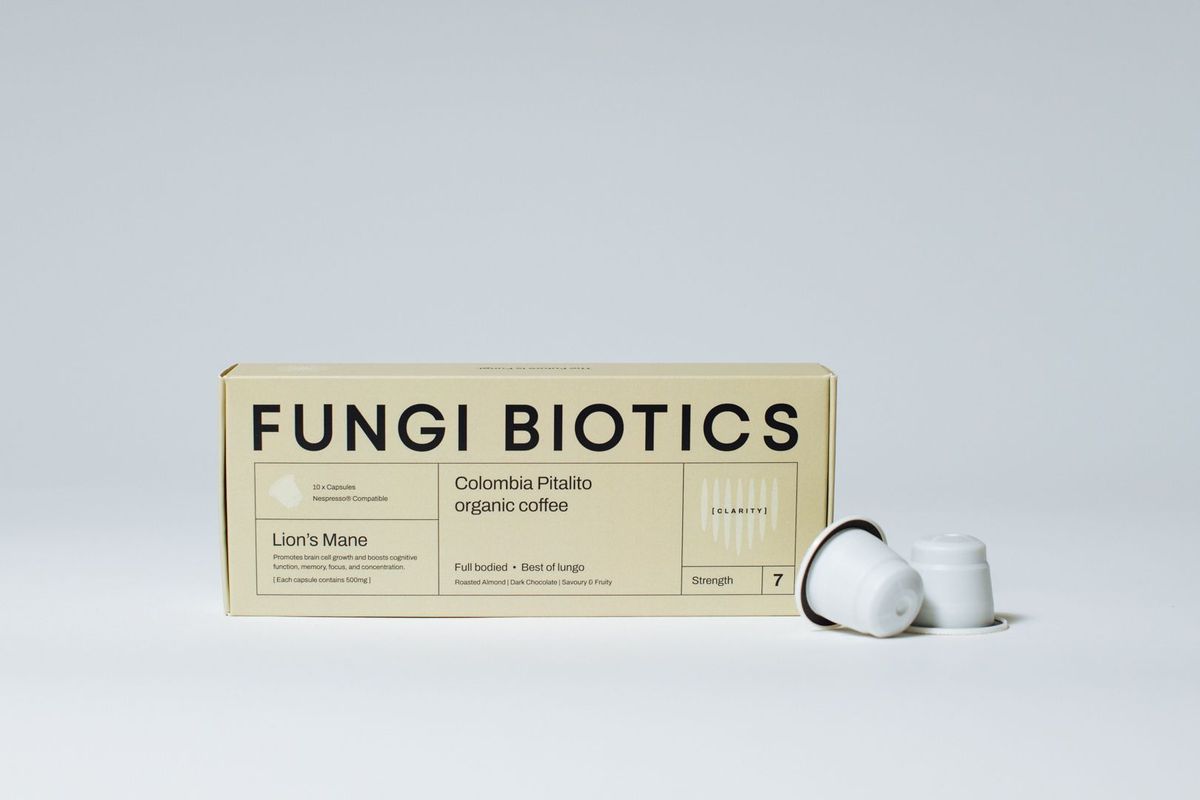 Fungi Biotics Lion's Mane coffee capsule box beside two capsules on a pale studio backdrop, by REGO Creative