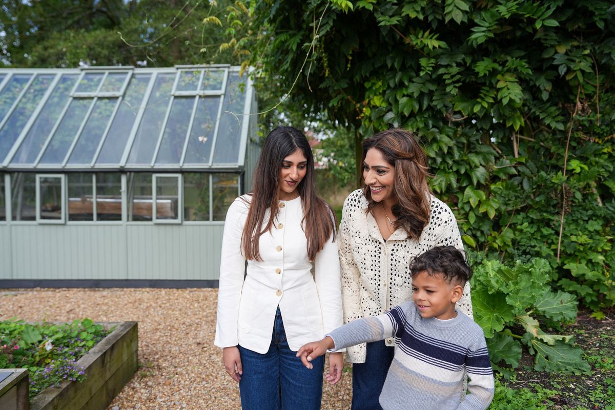 Two women and a young boy walking together in a garden beside a greenhouse, Lancashire County Council by REGO Creative