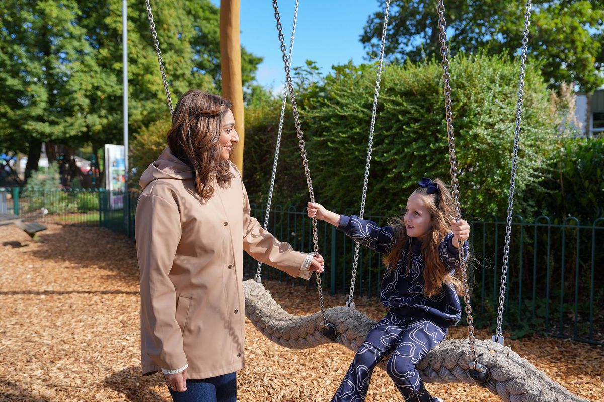 Foster carer standing beside a young girl on a rope swing in a park, Lancashire County Council by REGO Creative