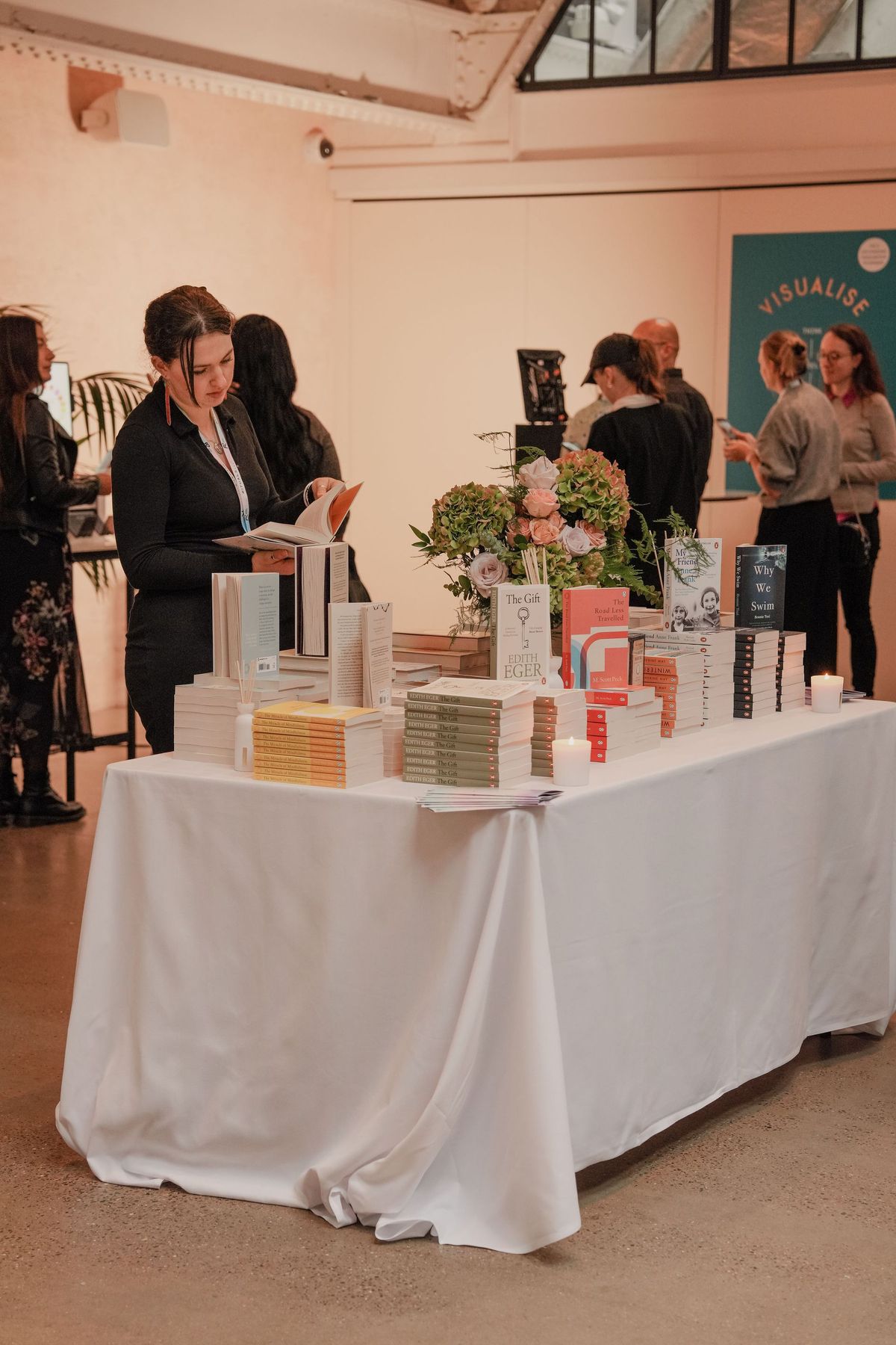 Guest browsing the book table with a flower arrangement at The Rider Reset event, Penguin Random House by REGO Creative