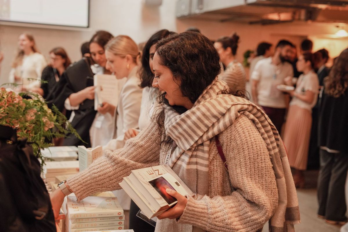 Guest smiling as she picks out books at The Rider Reset event, Penguin Random House by REGO Creative