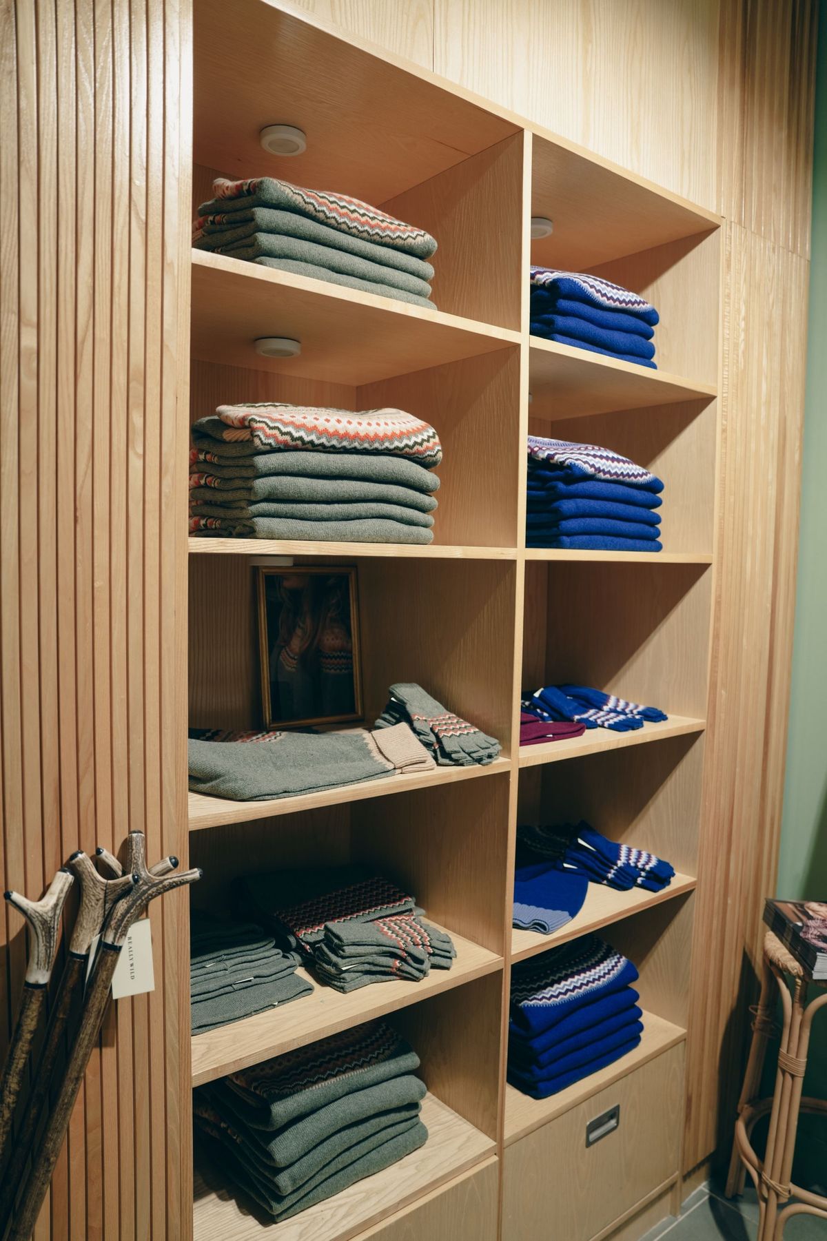 Shelves of green and blue Fair Isle knitwear in the Really Wild London shop, by REGO Creative