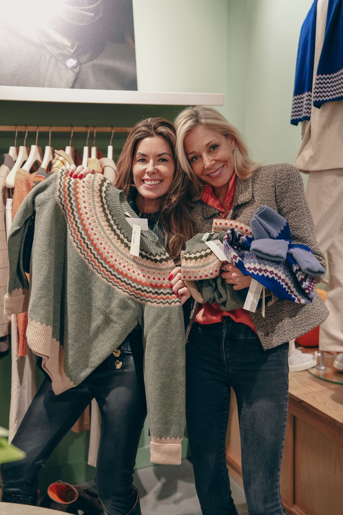 Two guests holding Fair Isle jumpers and accessories at the Really Wild x Sophie Stanbury launch, by REGO Creative