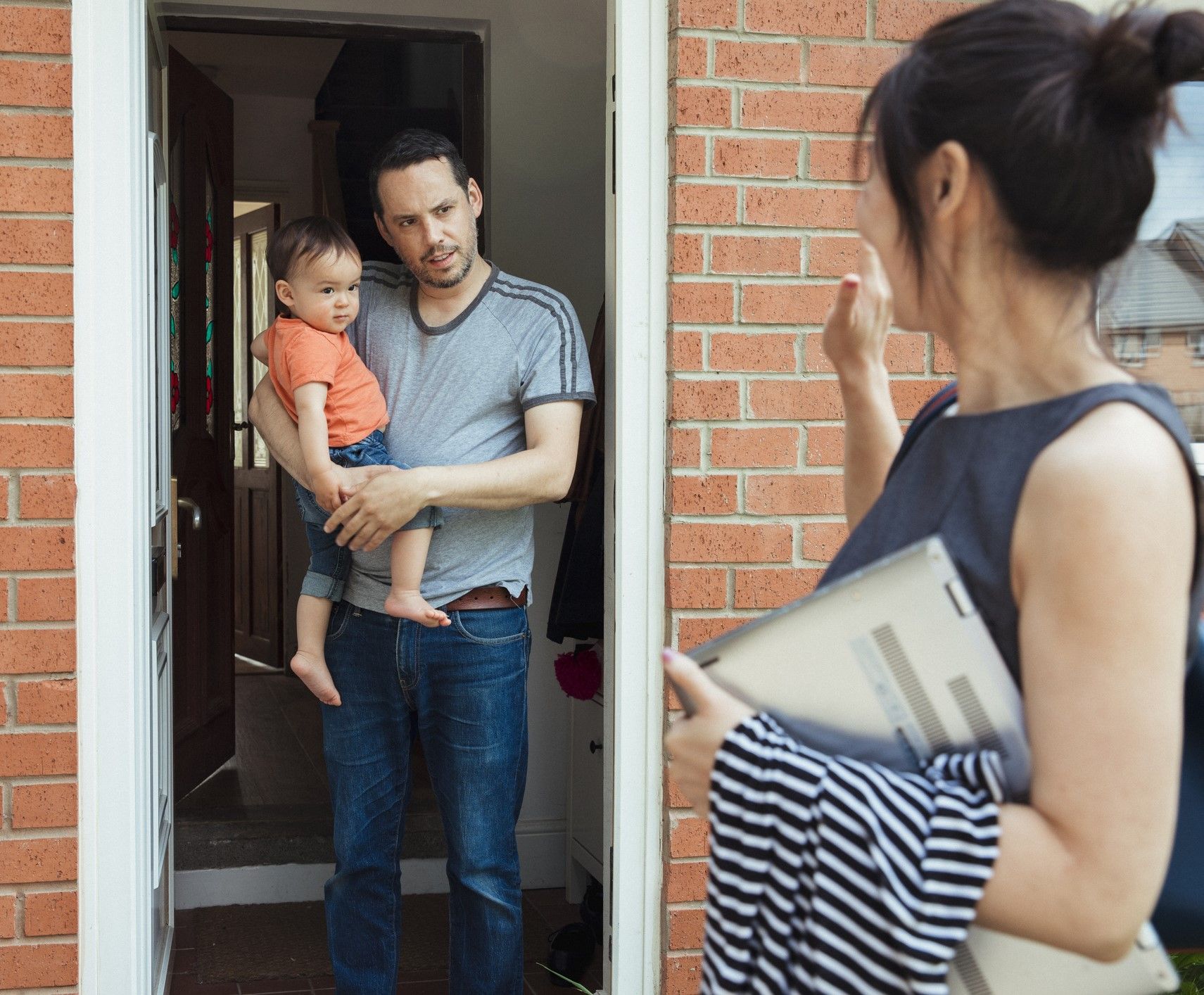 A man is holding a baby in his arms while a woman talks to him.