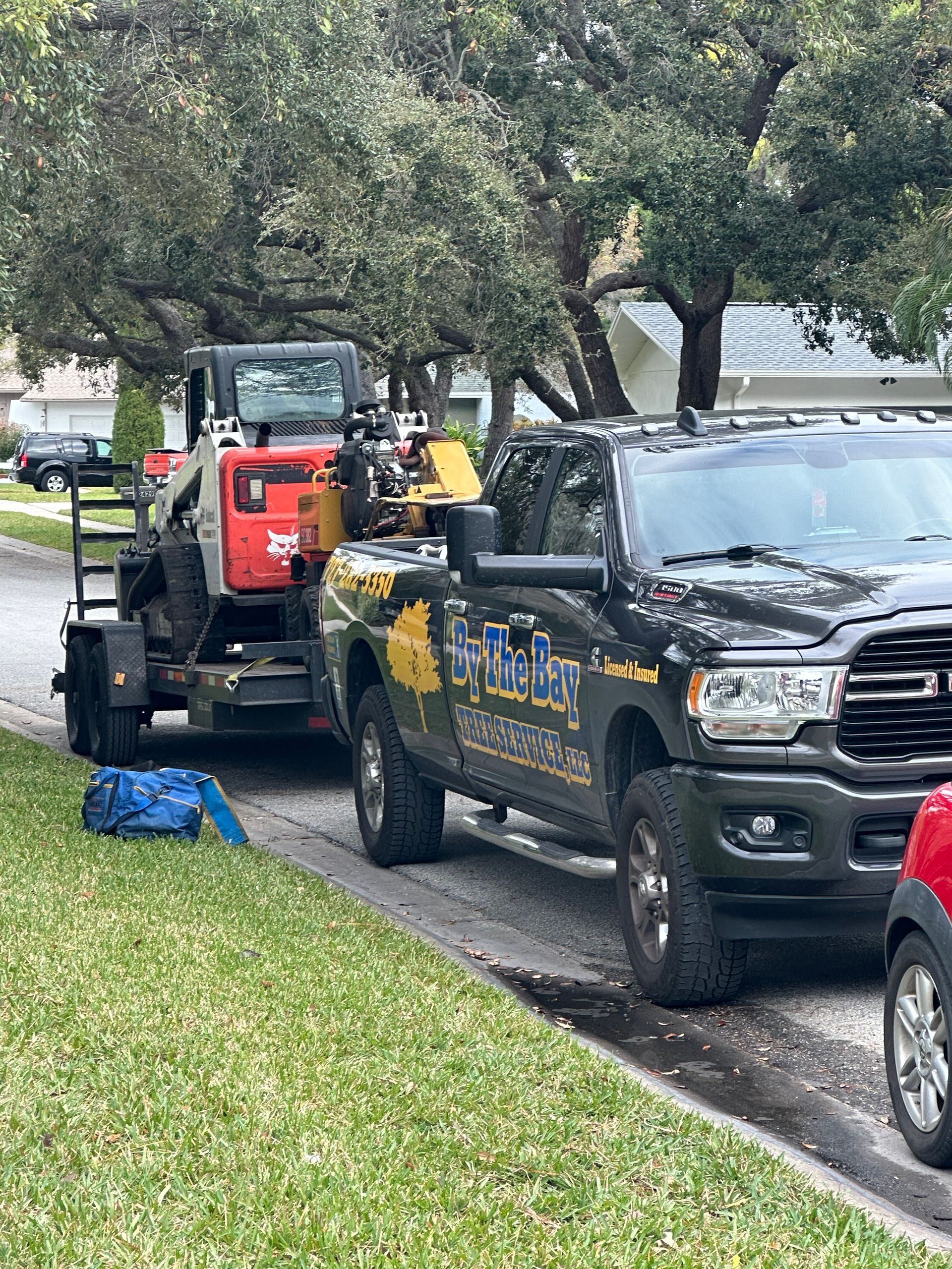 Tow truck loading a black pickup on a residential street, with another truck behind it.