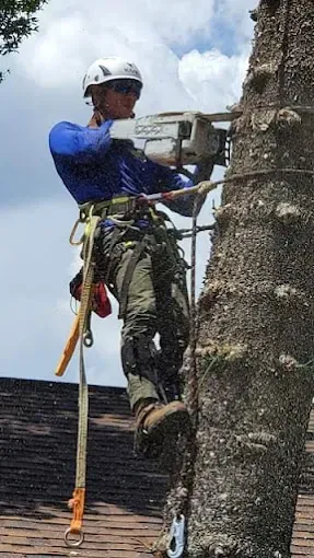 Rock climber in helmet and harness ascending a sheer rock face with safety rope attached