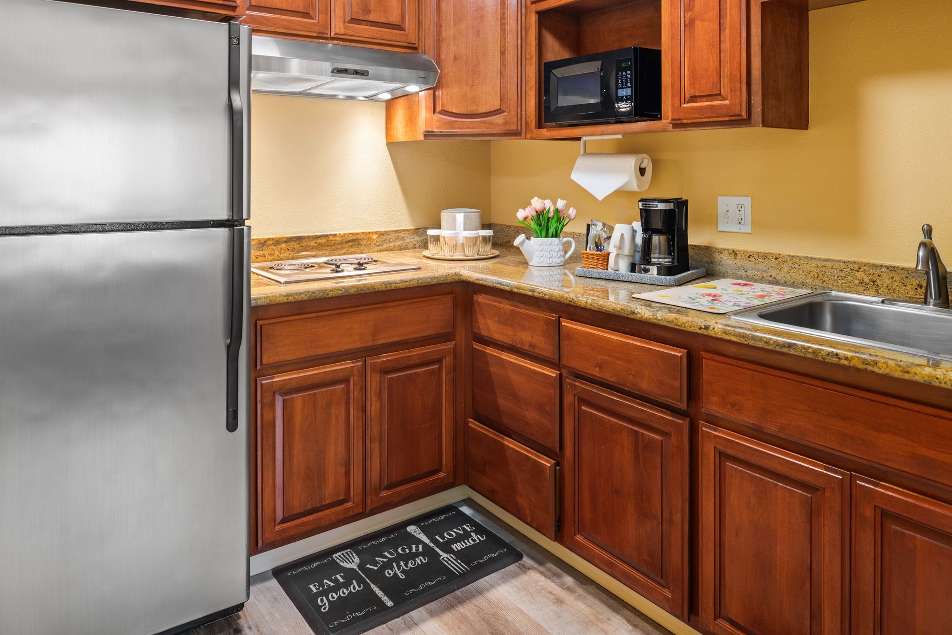 Kitchen with stainless steel fridge, wooden cabinets, granite counters, and coffee maker on the counter