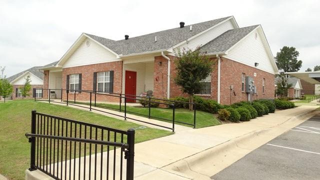A brick house with a red door and a handicap ramp