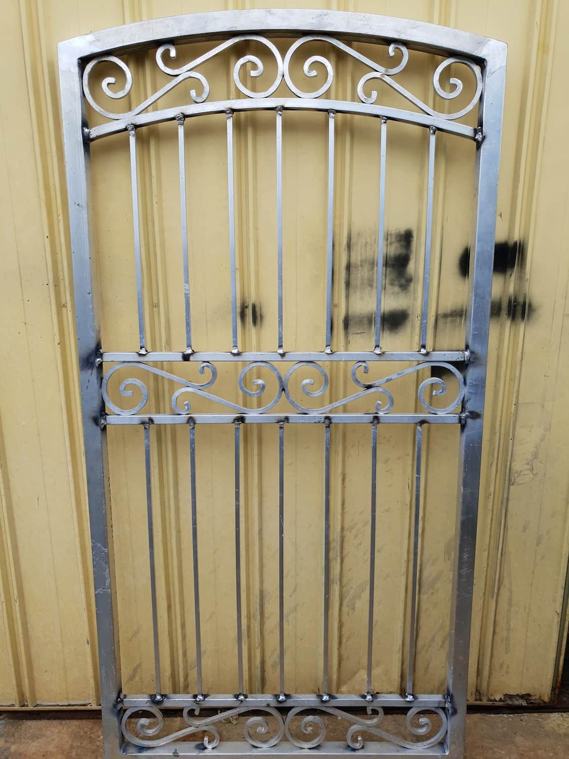 A Wrought Iron Gate Is Sitting In Front Of A Yellow Wall — DJ Welding & Services in Currajong, QLD 