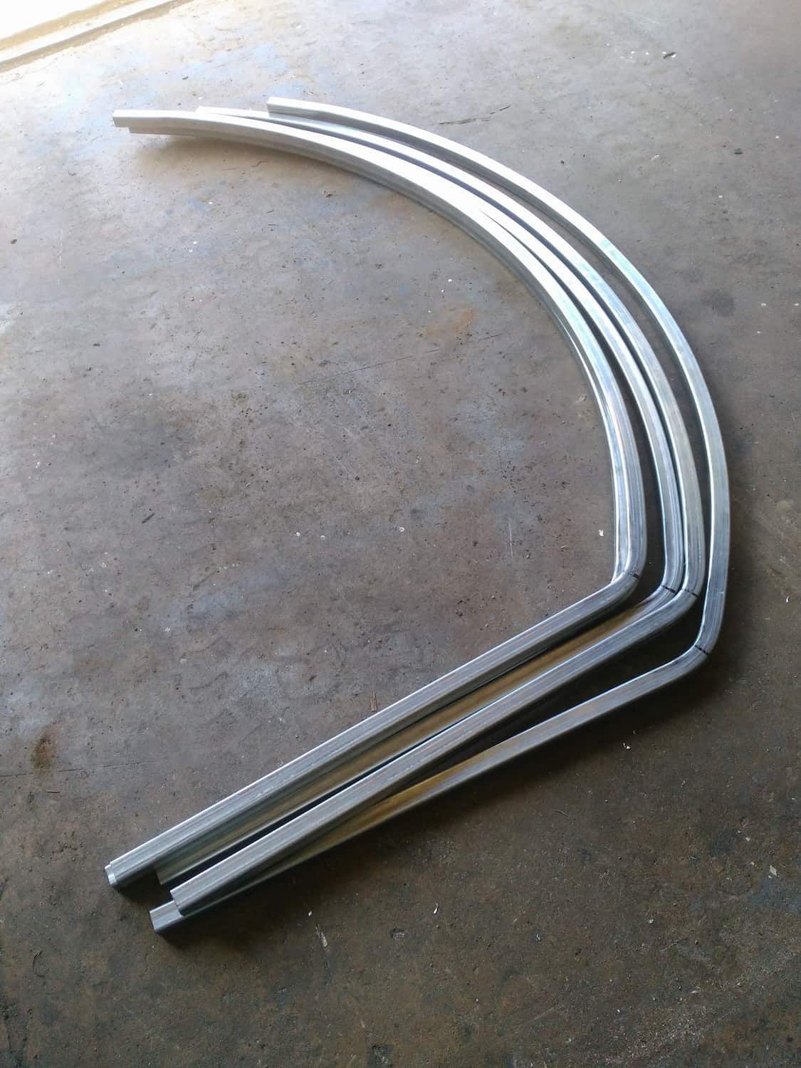 Three Pieces Of Metal Are Stacked On Top Of Each Other On A Concrete Surface — DJ Welding & Services in Currajong, QLD 