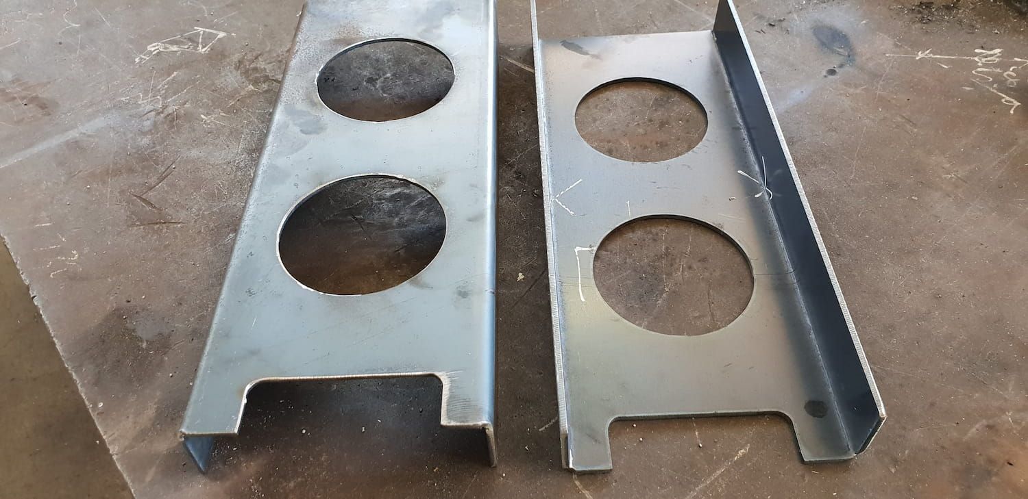 Two Metal Pieces With Holes In Them Are Sitting On A Table — DJ Welding & Services in Currajong, QLD 
