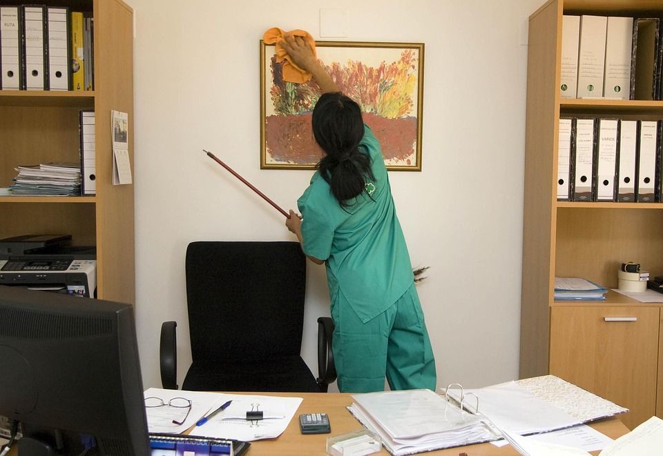 Una mujer con un traje verde está limpiando una oficina