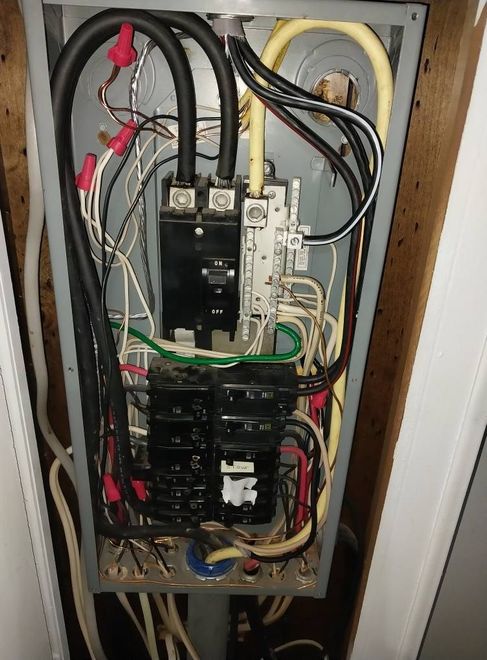 Open electrical breaker panel with wires and circuit breakers inside a wall cabinet
