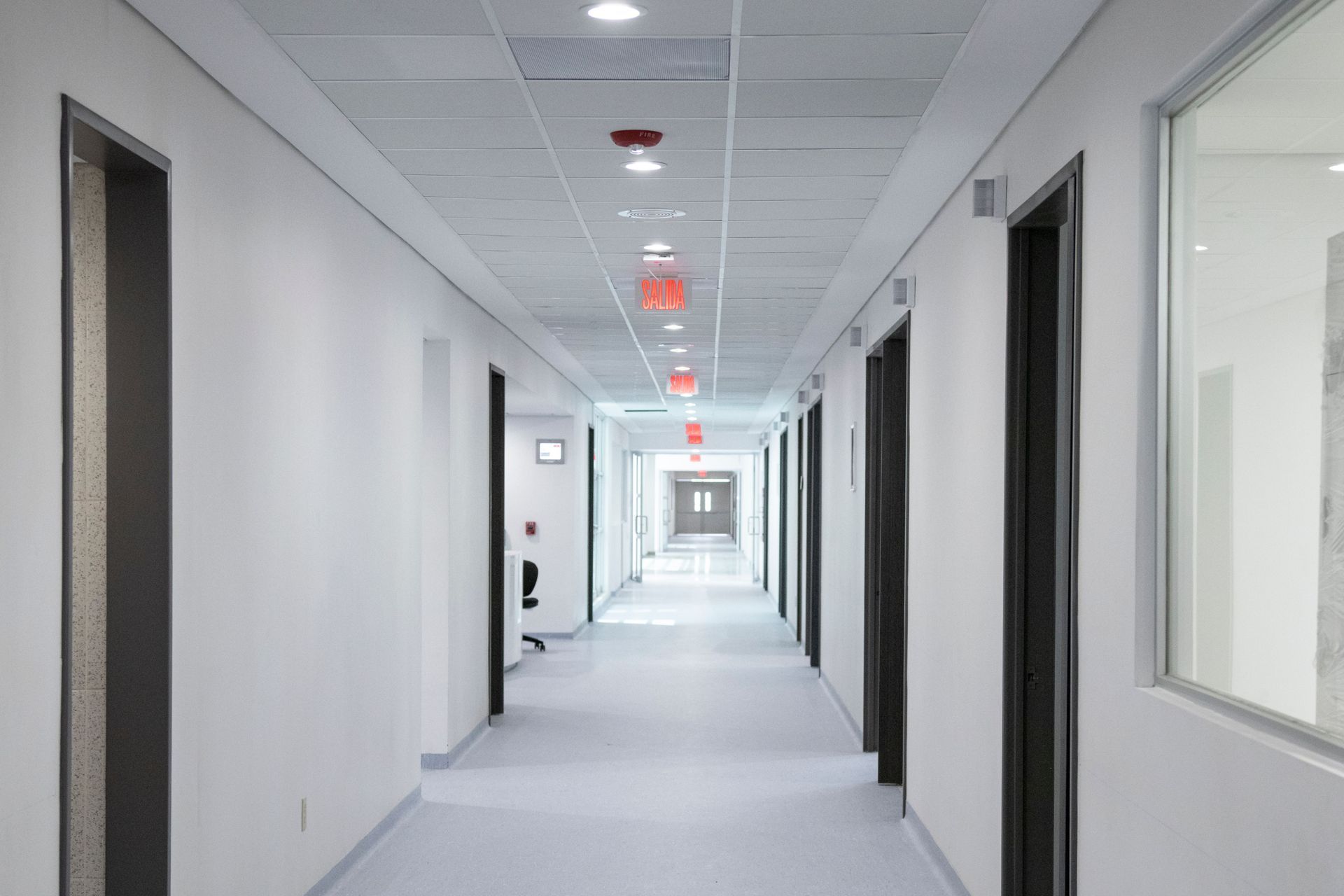 Bright office hallway with white walls, gray carpet, and red ceiling lights