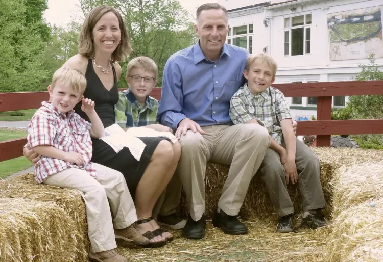 Family of four sitting on a bench in a front yard, smiling at the camera. Family of four sitting on a bench in a front yard, smiling at the camera.