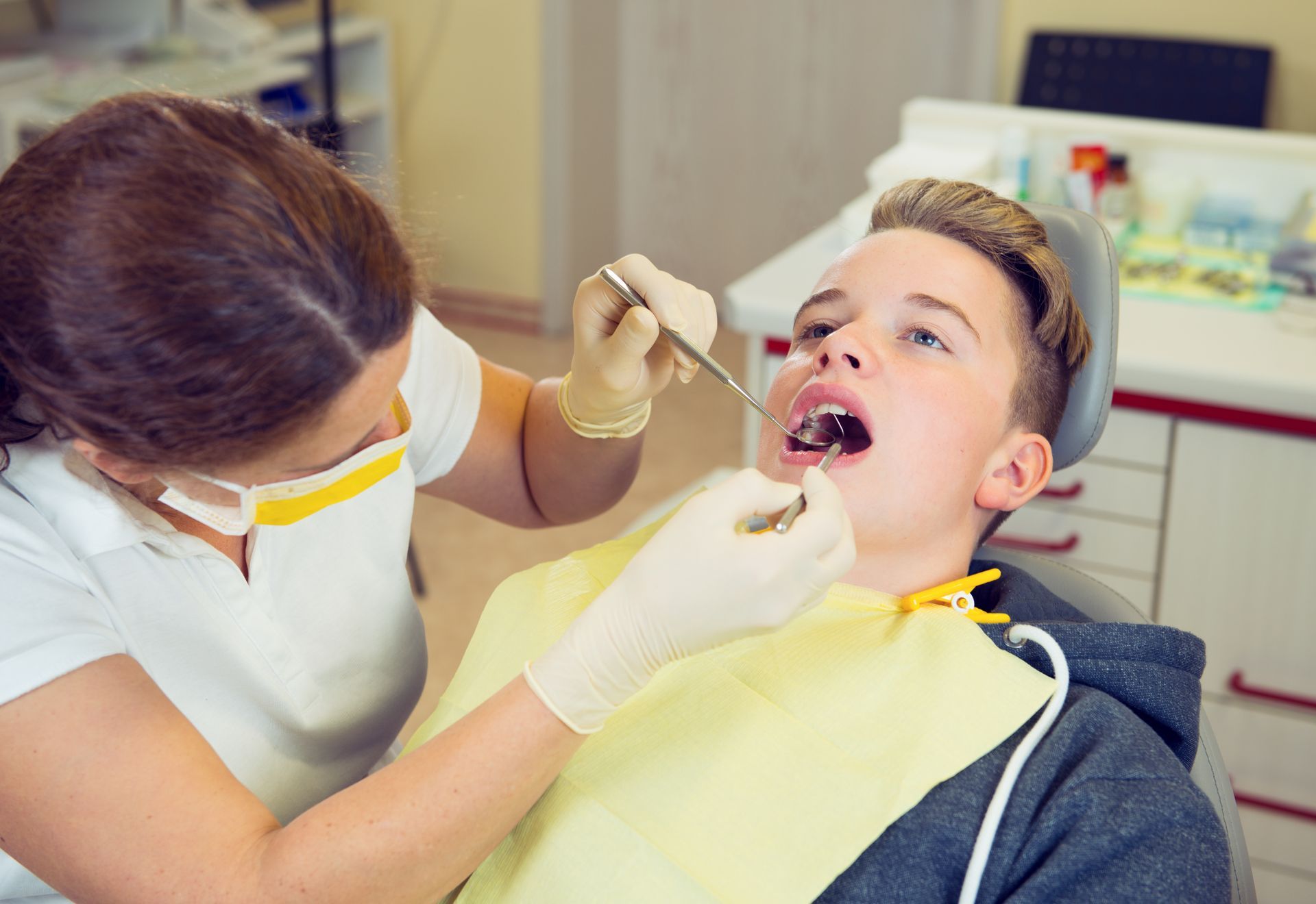 Dentist examining a patient’s open mouth in a dental clinic, wearing gloves and a mask
