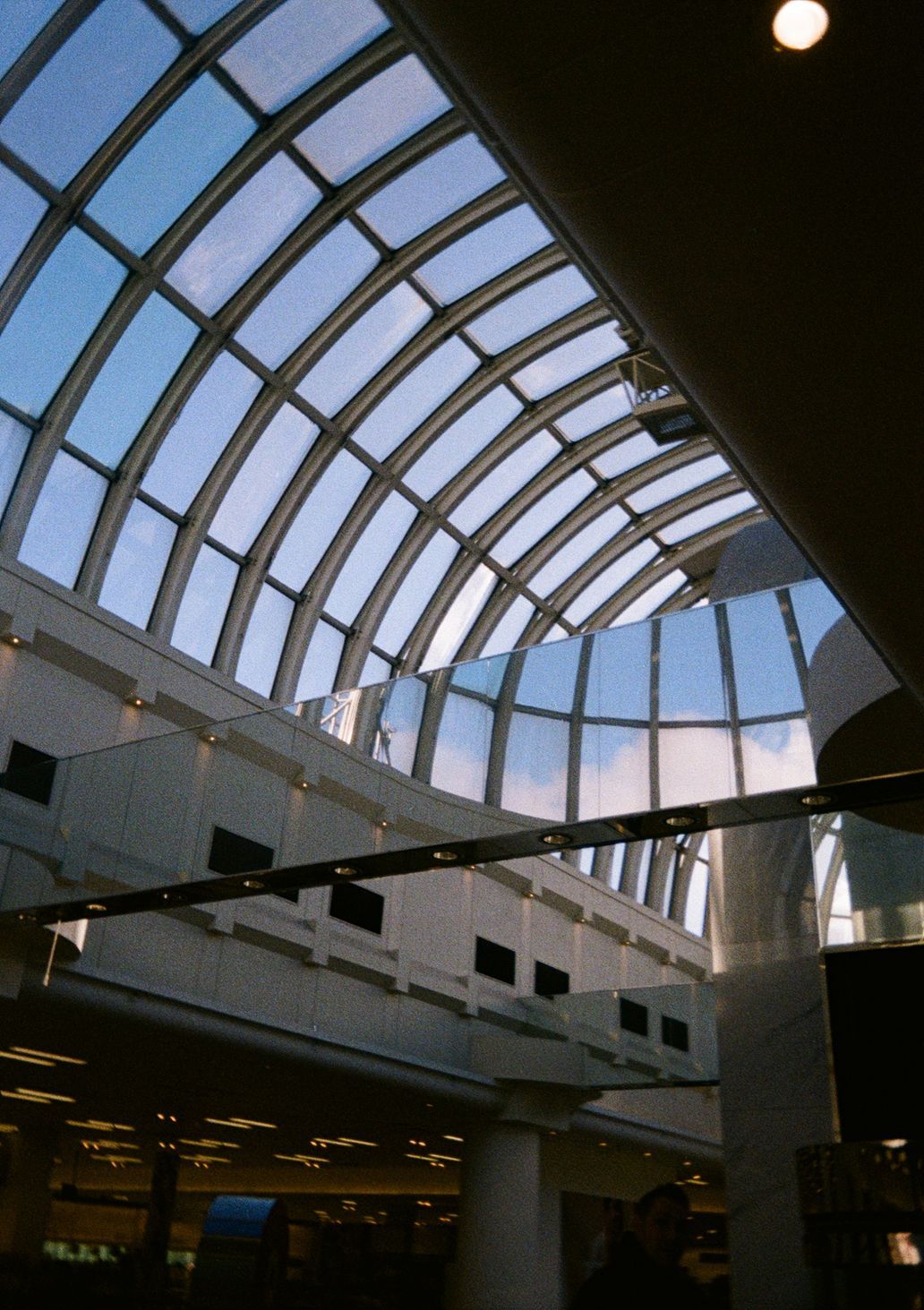 blue sky viewed through a large glass roof
