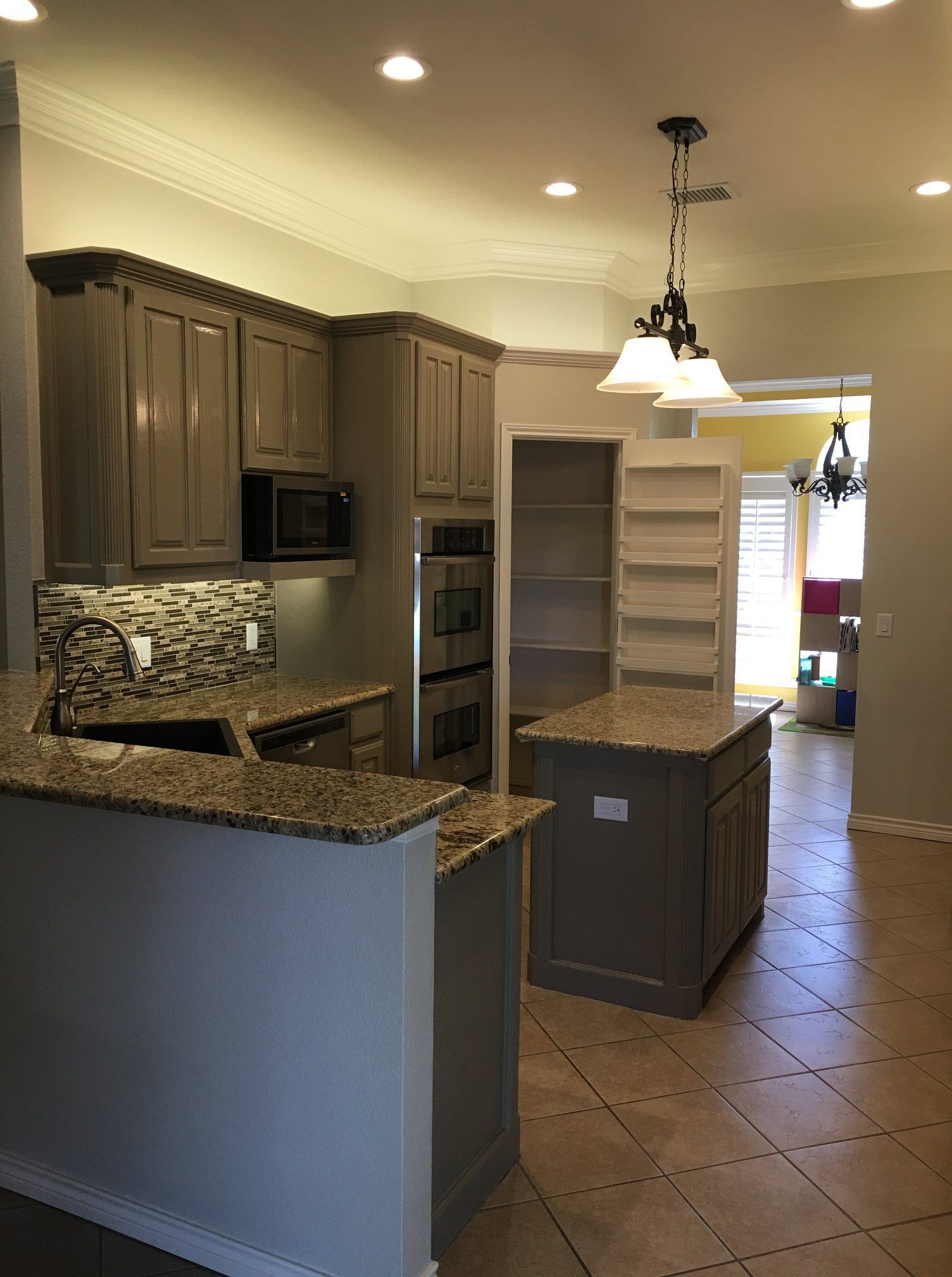 Kitchen with gray cabinets, granite countertops, and tile floor.