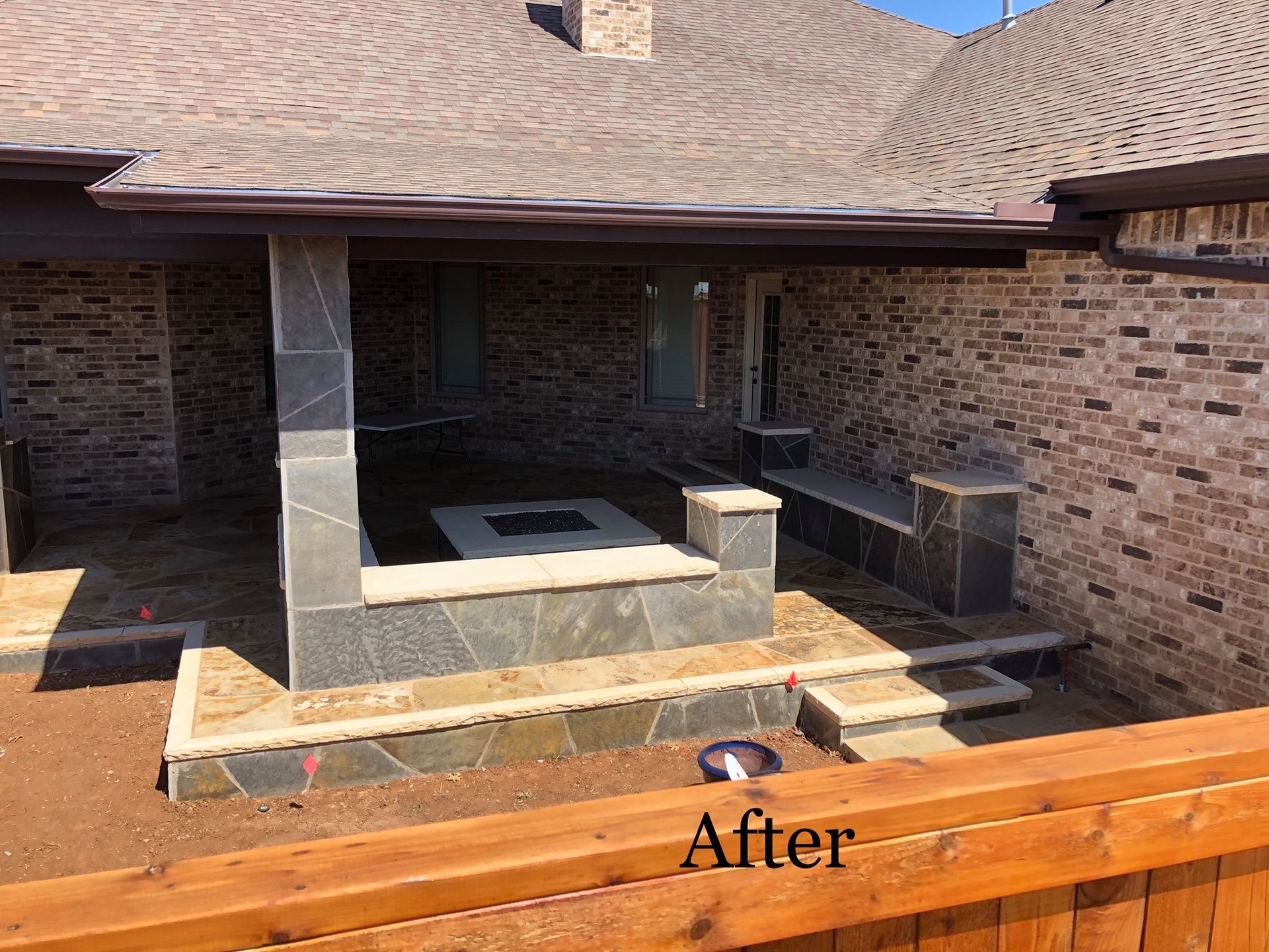 Backyard patio with stone fire pit, seating, and brick exterior.