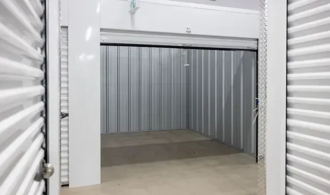 Open storage unit with gray corrugated metal walls and a concrete floor