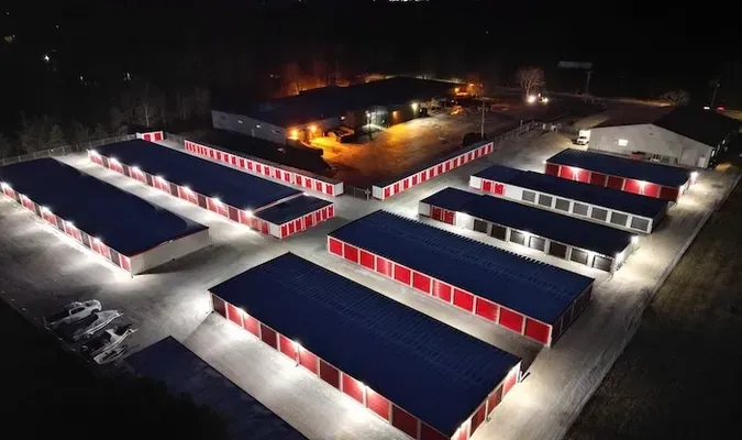 Long hallway in a storage facility with rows of white unit doors and overhead lights
