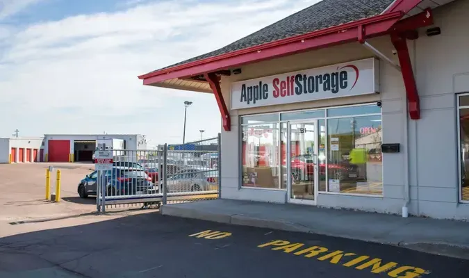 Apple Self Storage storefront with red roof, glass windows, and parking area outside