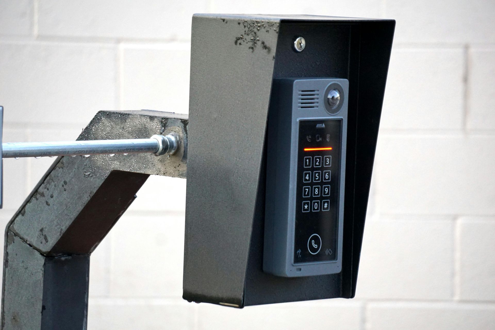 A black wall-mounted keypad on a metal post, likely for controlling access or a gate.