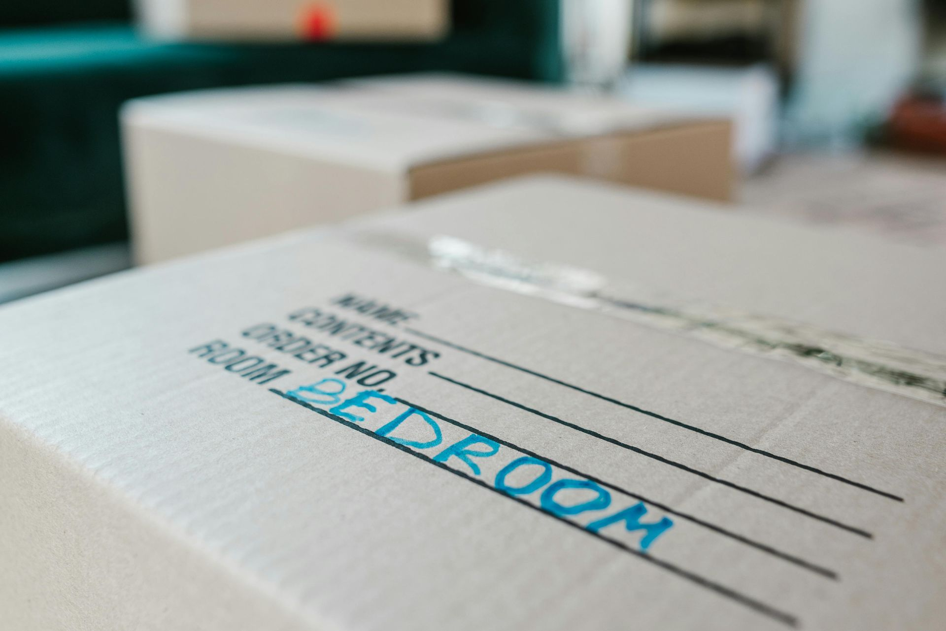 Close-up of white cardboard shipping boxes with blue labels on a blurred office desk