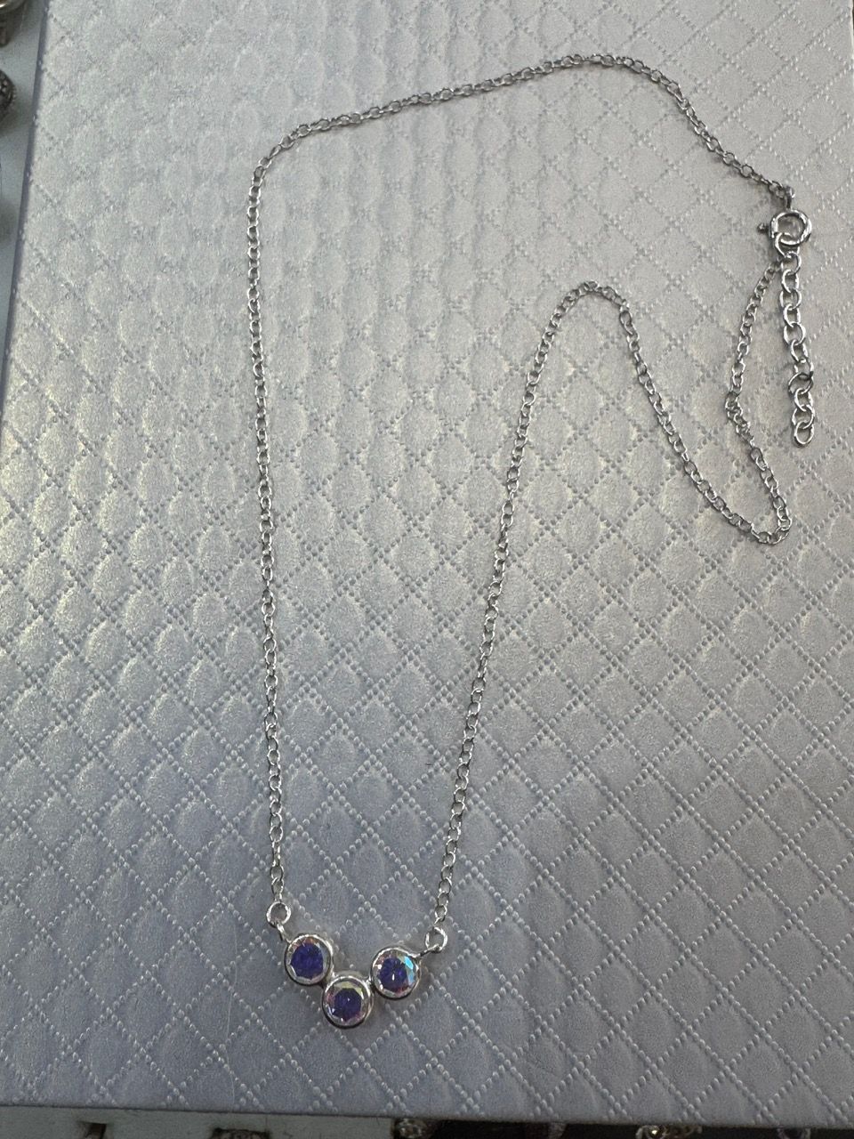 Collar de plata con tres piedras de color azul claro.