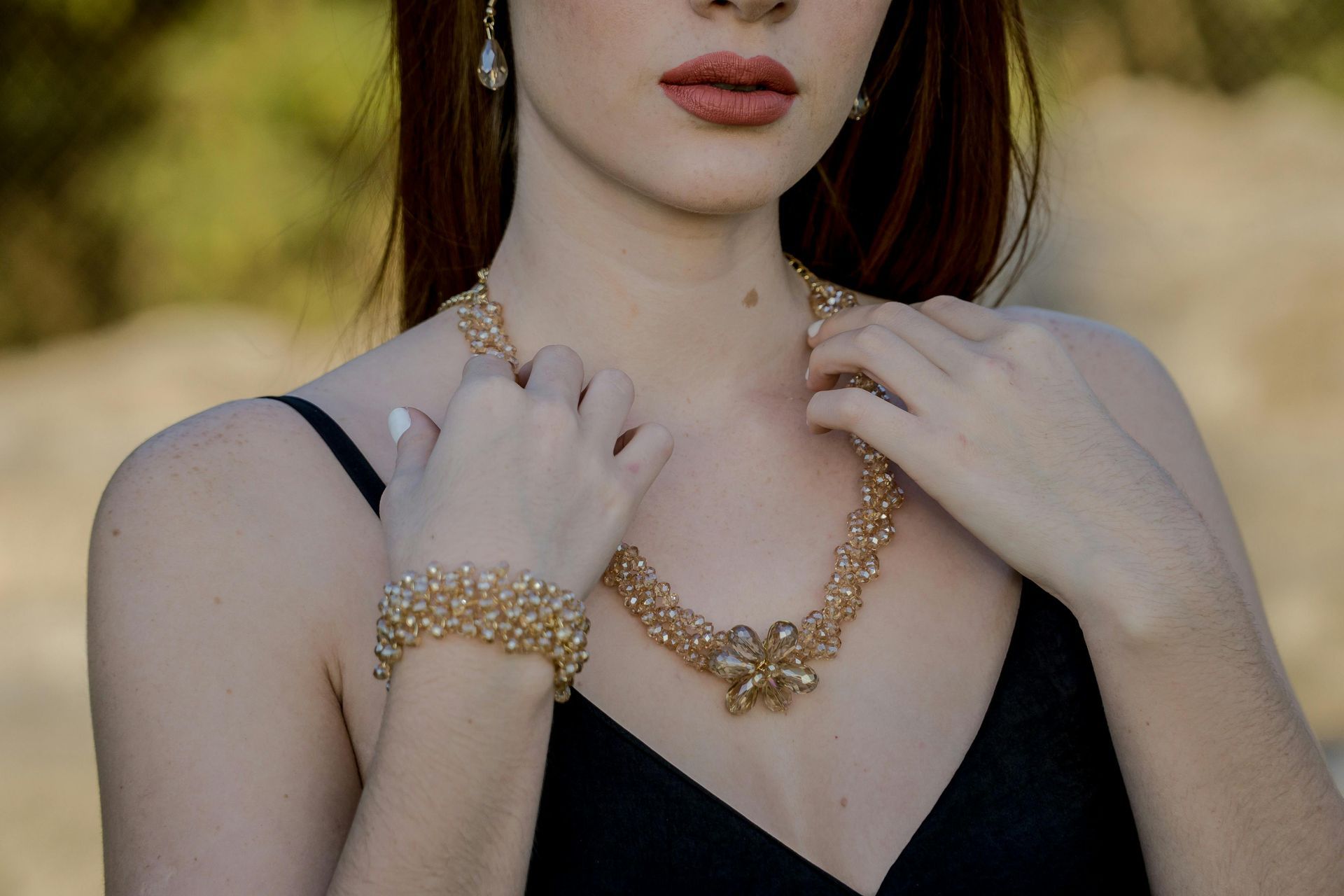 Una mujer con un vestido negro lleva un collar y una pulsera de oro.
