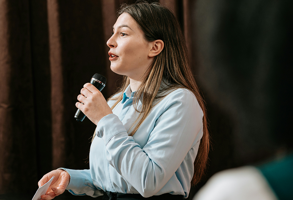 A woman is holding a microphone in her hand and speaking into it.