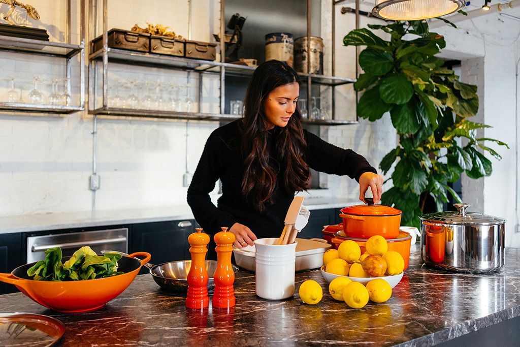 A woman is standing in a kitchen preparing food.