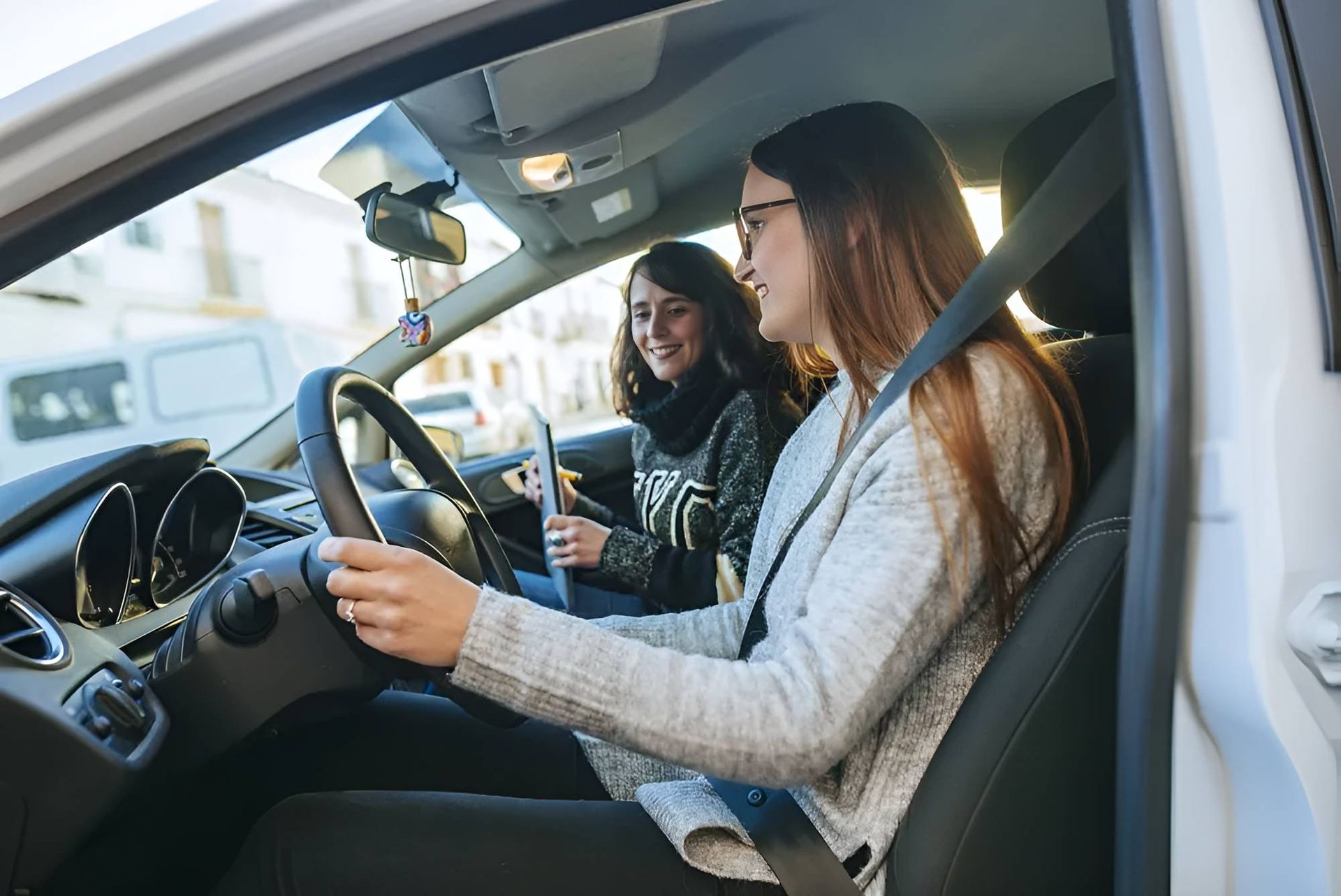 Two Young Women Are Sitting in a Car Looking at Their Phones — Casino Driving School In Casino, NSW