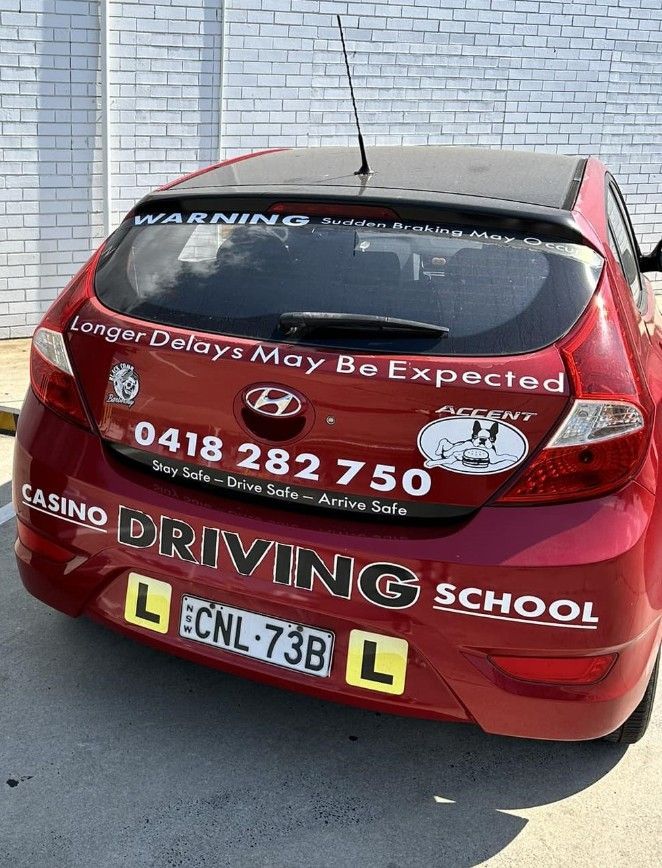A Red Car is Parked in Front of a White Brick Wall — Casino Driving School In Evans Head, NSW