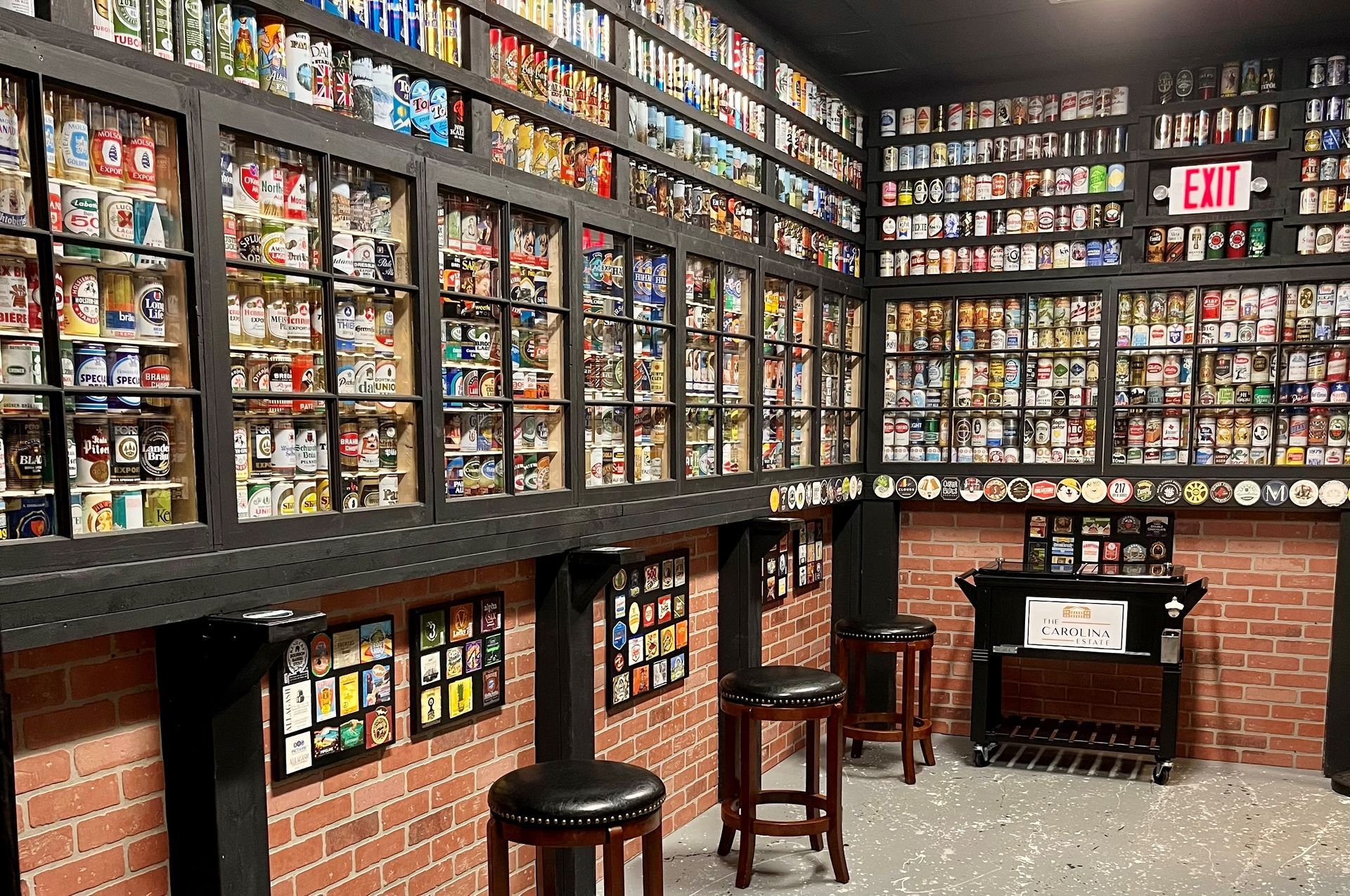Room with a collection of sports cards displayed in windowed cabinets on brick and black walls, and bar stools.