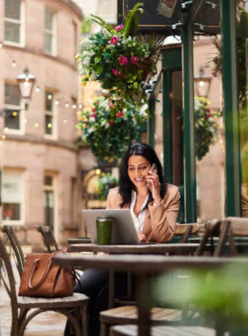 woman sitting at a table on her phone and laptop
